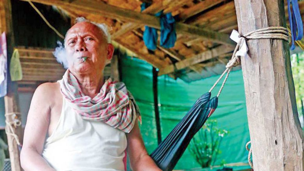 Meas Muth, former Khmer Rouge navy chief and war crimes suspect, smokes a cigarette at his house in Battambang in 2015. 