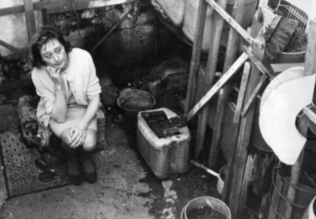 Mrs Joyce Eales sits in the yard of her home in Stepney, London after putting her four children into care because of rats attacking them in their slum dwelling